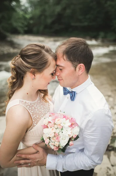 Ženich a nevěsta drží krásné svatební kytice. Jezero, lesní — Stock fotografie