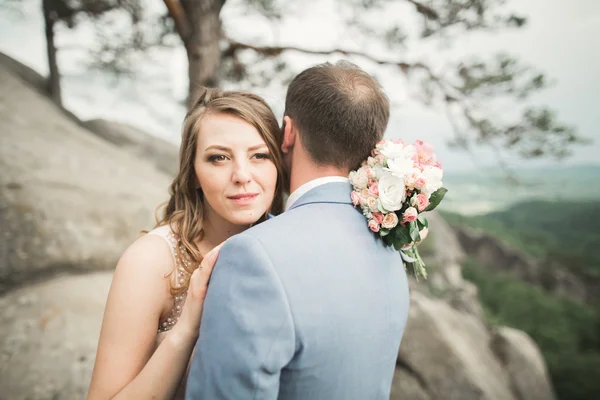 Linda noiva, noivo beijando e abraçando perto das falésias com vistas deslumbrantes — Fotografia de Stock