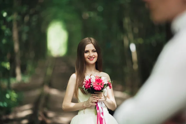 Braut posiert und lächelt, während Bräutigam im Hintergrund wartet — Stockfoto