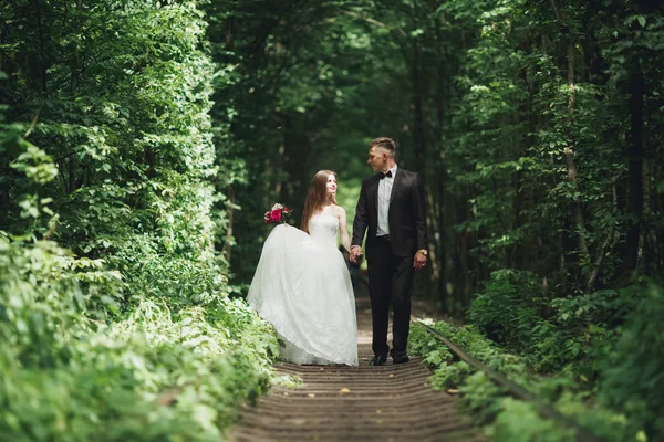 Jonge bruidspaar, bruid en bruidegom poseren op een spoor — Stockfoto