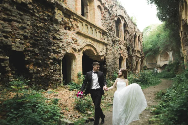 Novomanželům pózy a líbání s staré pevnosti na pozadí — Stock fotografie