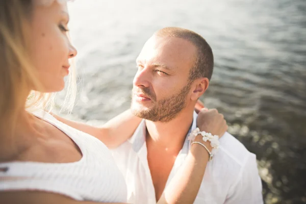 Romantica coppia amorevole posa su pietre vicino al mare, cielo blu — Foto Stock