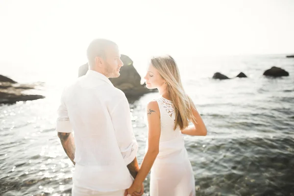 Hochzeitspaar küsst und umarmt sich auf Felsen nahe blauem Meer — Stockfoto