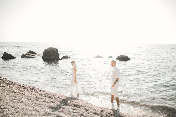 刚结婚的婚礼夫妇海滩上散步，在日落时分. — 图库照片