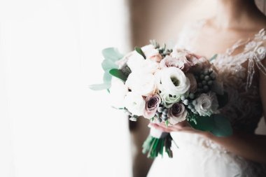 Gelin çiçekli büyük ve güzel bir düğün buketi tutuyor.