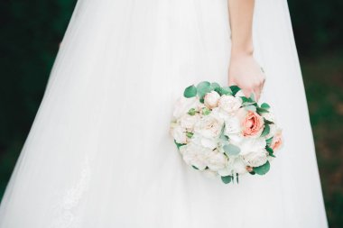 Gelin çiçekli büyük ve güzel bir düğün buketi tutuyor.