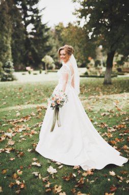 Gelin çiçekli büyük ve güzel bir düğün buketi tutuyor.