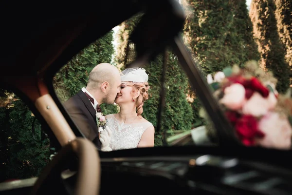 Boldog házaspár newlywed, a férj és a feleség közelében stílusos retro autó csók — Stock Fotó