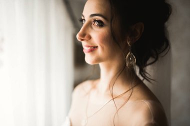 Cüppeli muhteşem gelin bir odada düğün töreni için poz veriyor ve hazırlanıyor.