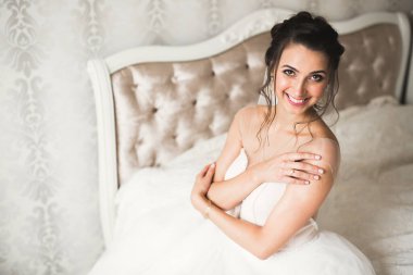 Cüppeli muhteşem gelin bir odada düğün töreni için poz veriyor ve hazırlanıyor.