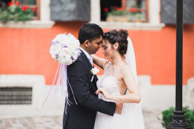 Muhteşem mutlu çift birbirine yakın duruyor ve eski şehir geçmişine, düğün fotoğrafına, Avrupa şehrine, Lviv 'de düğün gününe bakıyor.