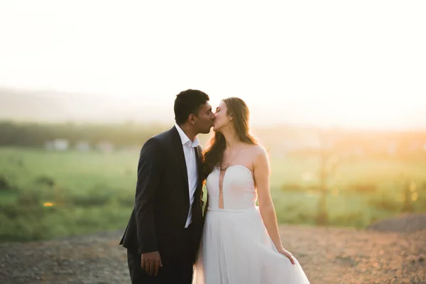 Bela noiva e noivo abraçando e beijando em seu dia de casamento ao ar livre — Fotografia de Stock