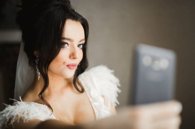 Güzel, gülümseyen bir gelin telefonda selfie çekiyor.