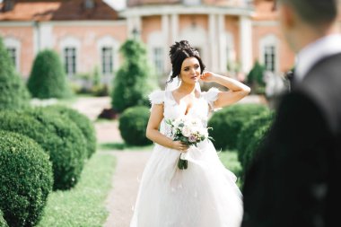 Çekici gelinin portresi, uzun saçlı, büyük buketli poz veren.