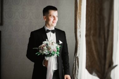 Güzel adam, damat elinde çiçeklerle büyük ve güzel bir düğün buketi tutuyor