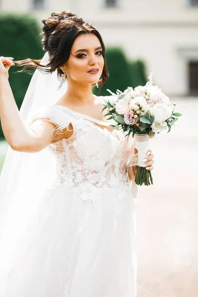 Gyönyörű luxus fiatal menyasszony esküvői ruha pózol a parkban — Stock Fotó