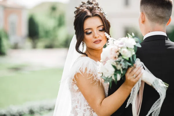 Vackra unga bröllop par poserar med bukett blommor i händerna — Stockfoto