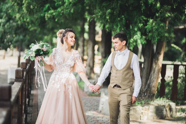 Стильна пара щасливих молодих людей, що гуляють в парку в день весілля з букетом — стокове фото