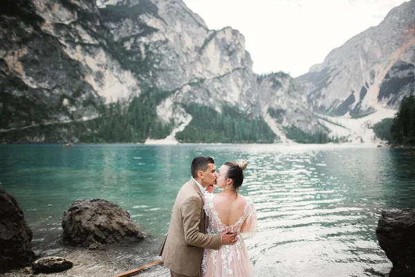 Couple de mariage sur la nature se serre dans les bras près d'un beau lac dans les montagnes.. Belle fille modèle en robe blanche. Homme en costume — Photo