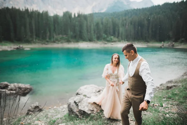 Pareja joven cerca del lago Karersee, Italia. Tomando de la mano en la piedra en el lago — Foto de Stock