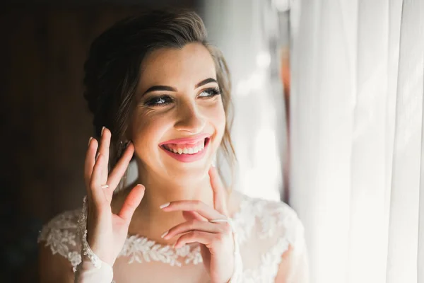 Preciosa novia en bata posando y preparándose para la ceremonia de boda cara en una habitación —  Fotos de Stock