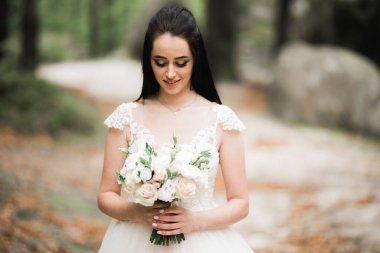 Gelin çiçekli büyük ve güzel bir düğün buketi tutuyor.