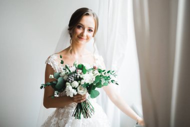 Gelin çiçekli büyük ve güzel bir düğün buketi tutuyor.