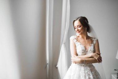 Cüppeli muhteşem gelin bir odada düğün töreni için poz veriyor ve hazırlanıyor.