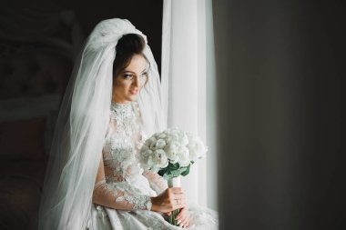 Gelin çiçekli büyük ve güzel bir düğün buketi tutuyor.