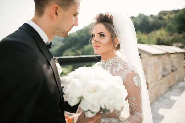 Beautiful young wedding couple posing with bouquet of flowers in hands — Stock Photo, Image