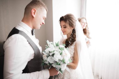 Gelin, damat ceketine yeşil yapraklı beyaz yaka çiçeğini iğneledi.