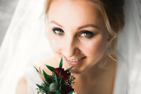 Hermosa novia con vestido de novia de moda con plumas con maquillaje de lujo deleite y peinado, estudio sesión de fotos interior — Foto de Stock