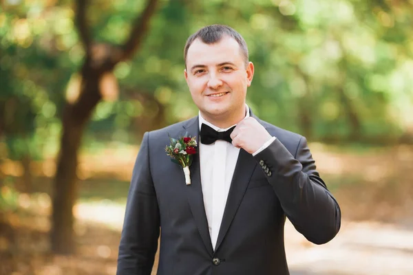 Happy handsome smiling groom posing with boutonniere — Stock Photo, Image