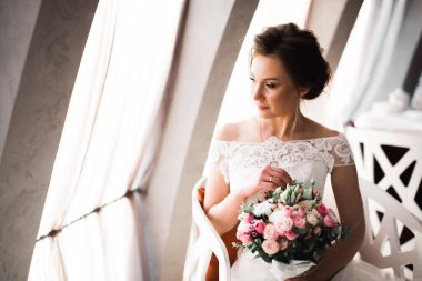 Gelin çiçekli büyük ve güzel bir düğün buketi tutuyor.