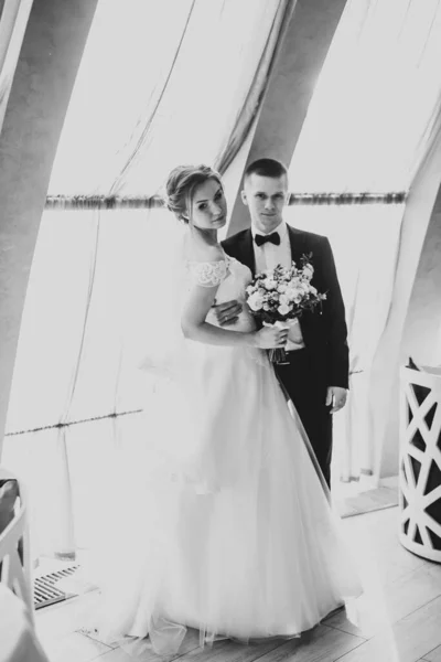 Pasangan pengantin muda yang cantik berpose dengan karangan bunga di tangan — Stok Foto