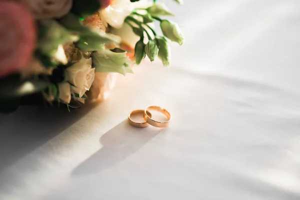 Imagem tonificada bonita com anéis de casamento contra o fundo de um buquê de flores — Fotografia de Stock