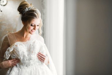 Beyaz elbiseli lüks gelin düğün törenine hazırlanırken poz veriyor.