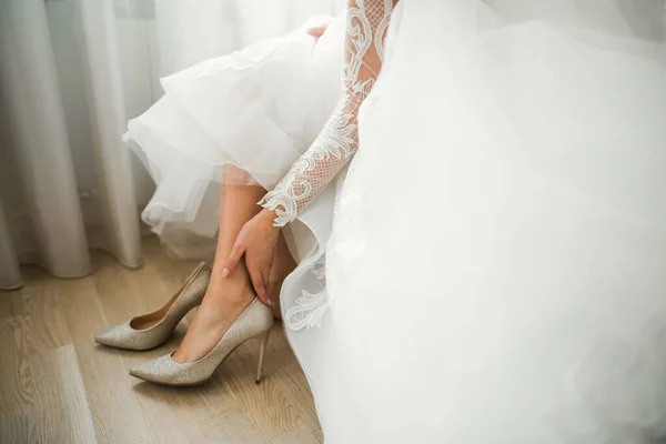 Braut zieht elegante und stylische Brautschuhe an ihren zarten Füßen an — Stockfoto