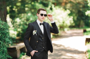 Yaka çiçeğiyle poz veren mutlu yakışıklı damat.