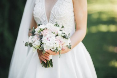 Gelin çiçekli büyük ve güzel bir düğün buketi tutuyor.