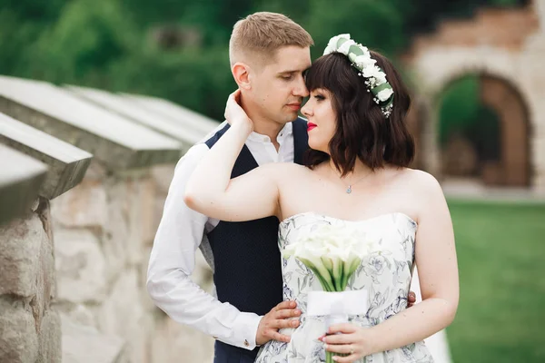 Romantique, conte de fées, couple de jeunes mariés heureux embrassant et embrassant dans un parc, arbres en arrière-plan — Photo