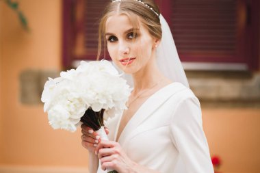 Lüks bir gelin, bir kız buketle poz veriyor ve gülümsüyor.