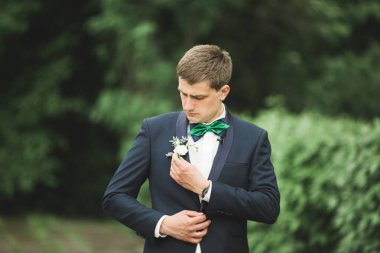 Yaka çiçeğiyle poz veren mutlu yakışıklı damat.