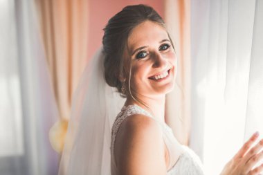 Beyaz elbiseli lüks gelin düğün törenine hazırlanırken poz veriyor.