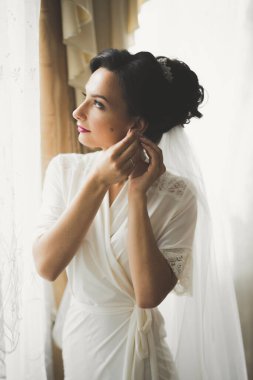 Cüppeli muhteşem gelin bir odada düğün töreni için poz veriyor ve hazırlanıyor.