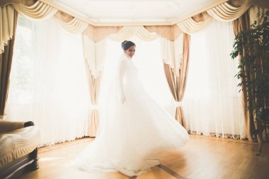 Cüppeli muhteşem gelin bir odada düğün töreni için poz veriyor ve hazırlanıyor.