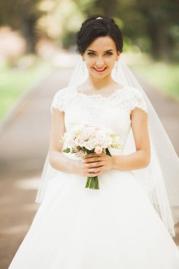 Çekici gelinin portresi, uzun saçlı, büyük buketli poz veren.