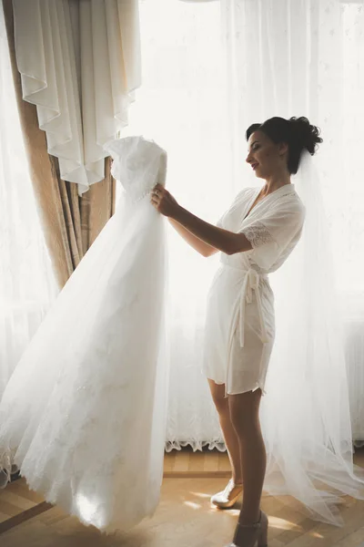 Linda noiva em roupão posando e se preparando para o rosto cerimônia de casamento em uma sala — Fotografia de Stock