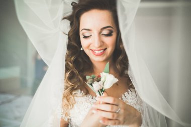 Beyaz elbiseli lüks gelin düğün törenine hazırlanırken poz veriyor.