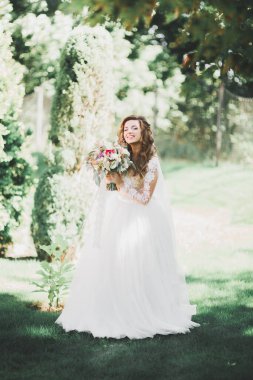 Parkta poz veren zarif beyaz elbiseli güzel gelin.